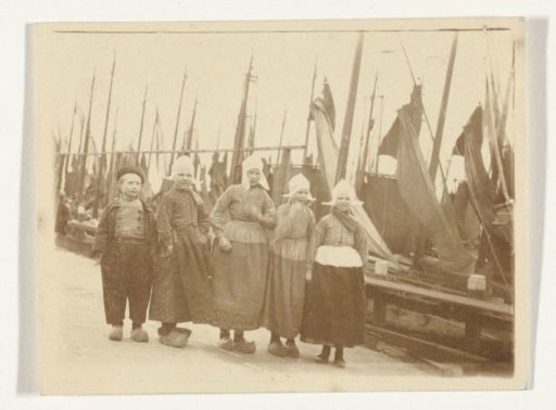 Group portrait of five unknown children in traditional dress in the harbor of Volendam
