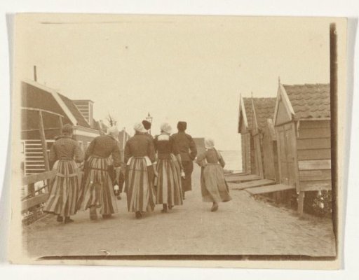 Men, women and a girl in traditional dress in Volendam, with the Zuiderzee in the distance
