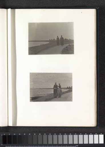 Two women in Volendam costume standing on a dike