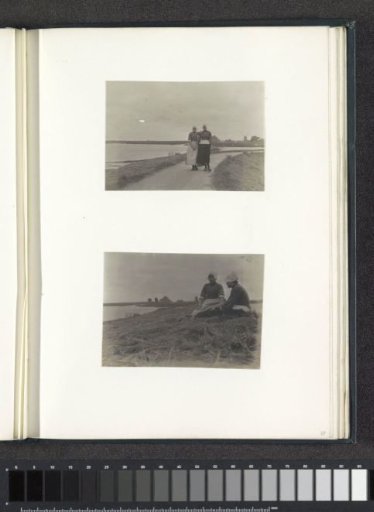 Two women in Volendam costume walking on a dike