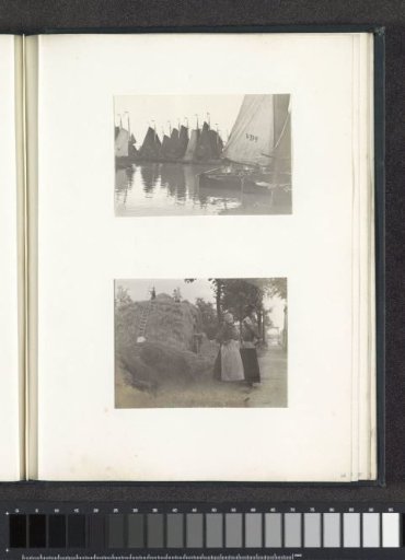 Two women in Volendam costumes standing by a haystack