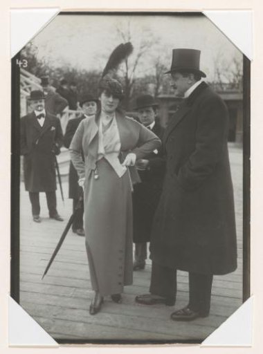 Woman with a feather on her hat among some men, possibly during horse races at the Hippodrome de Longchamp in the Bois de Boulogne