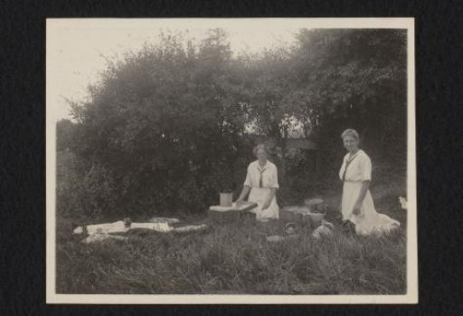 Two women preparing food in the grass