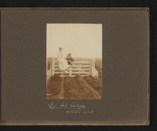 Woman sitting on a fence, man standing beside her