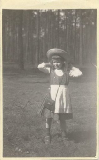 Marba Titzenthaler, daughter of the photographer, standing before a forest