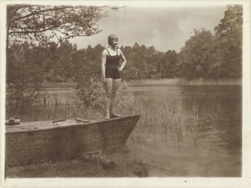 Unknown young woman in a bathing suit in a rowing boat on the edge of a lake