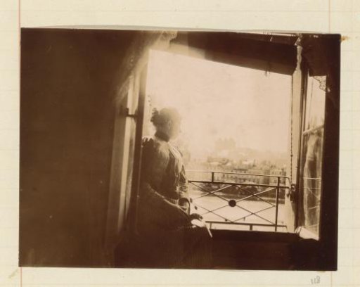 Woman seated in an open window, looking out over a river