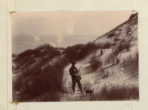 Hunter in the dunes, standing with a dog