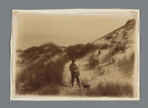 Hunter in the dunes, standing with a dog