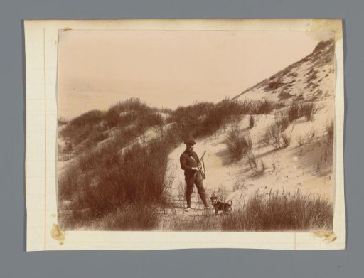 Hunter in the dunes, standing with a dog