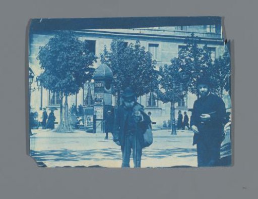 Street scene with French-language advertising column and passersby