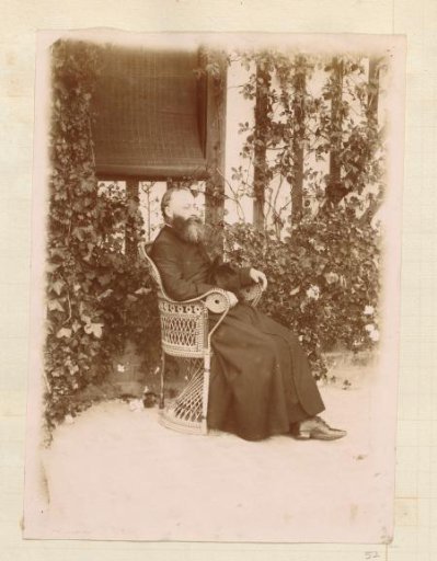 Portrait of a Catholic priest in a wicker chair