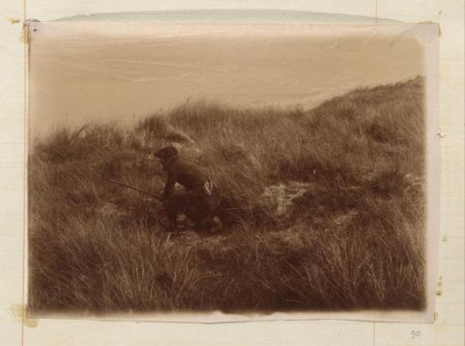 Hunter in the dunes, sitting bent over