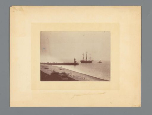Tugboat towing a sailing ship at a harbor pier