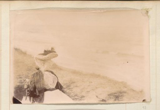 Portrait of a woman with a hat, veil and parasol, sitting on the beach