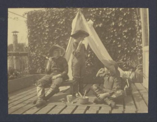 Three boys in costumes playing in a homemade tent on the balcony