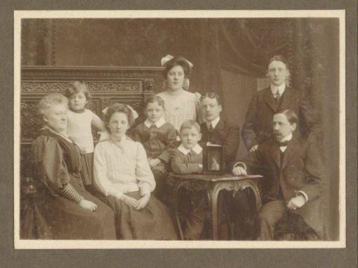 Group portrait of nine members of the Vermeulen family, including G. Vermeulen-Luitjes (left) and C.J.L. Vermeulen (right), with a photographic portrait of a woman on the table