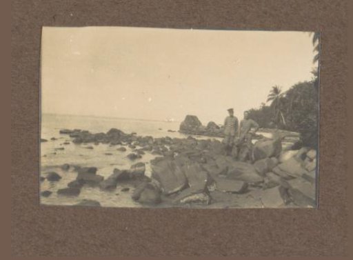 Two men in military uniform on rocks on the coast of the Dutch East Indies