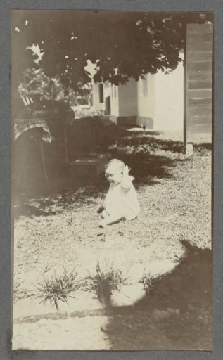 Eleven-month-old baby Tiny Kleiterp sitting on a grassy field in Madjene on Celebes