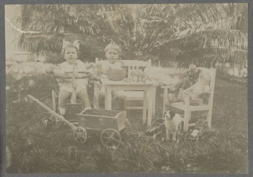 Klaas and Tiny Kleiterp sitting amidst toys in a garden in Madjene on Celebes