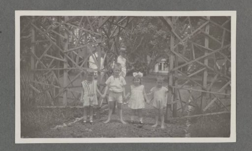 Four children holding hands in front of a wooden fence in Batoedjadjar