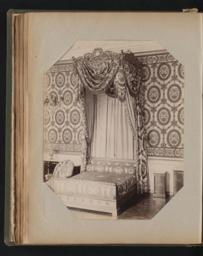 Canopy bed with ornaments, with decorative wallpaper featuring a floral pattern in the background