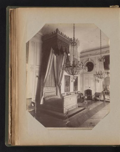 Canopy bed in a room with two chandeliers and furniture