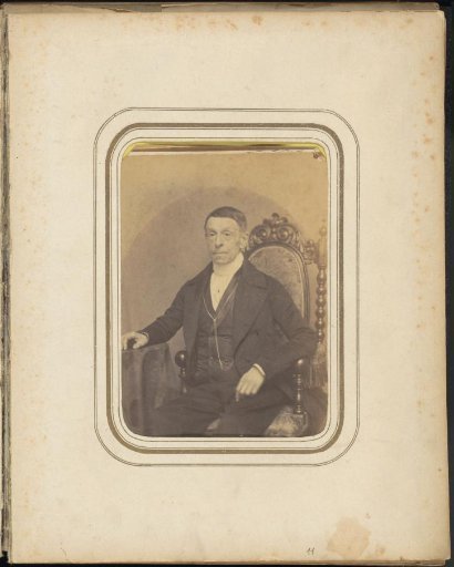 Portrait of a seated man in a long coat with a chain
