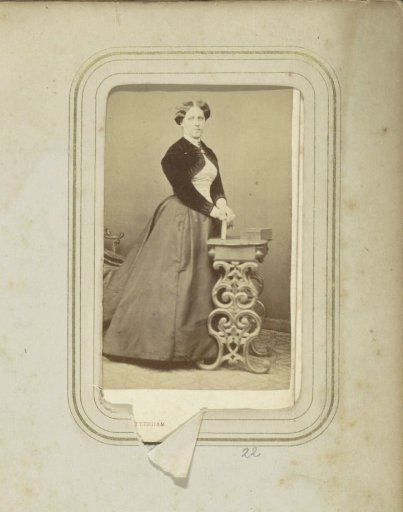 Portrait of a woman with a long skirt and a bolero at a small table