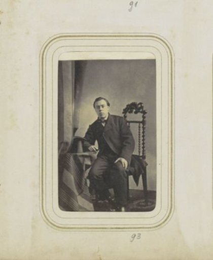 Portrait of a man at a table with a tall hat