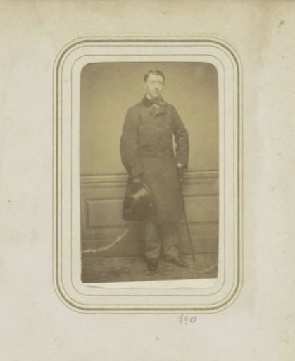 Portrait of a man in a long coat with a hat and a walking stick