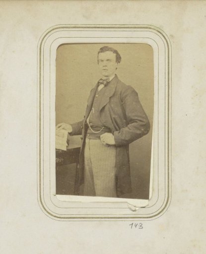 Portrait of a man in a long coat holding an open book
