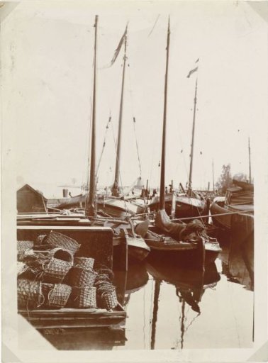 Jetty with wicker baskets and fishing boats in the harbor of Zaandam