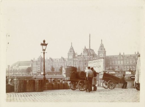 View of Central Station in Amsterdam, with the Prins Hendrikkade in the foreground, two carts and peddlers