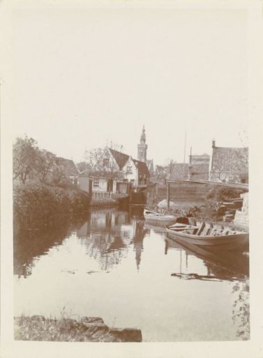 Canal with two skiffs in Edam, with the Speeltoren in the distance
