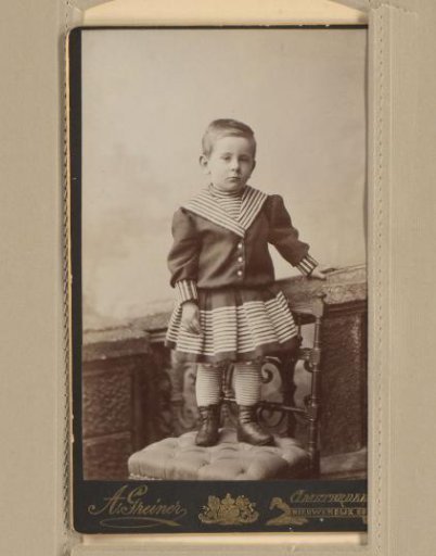 Studio portrait of a young Guus Kessler on a chair next to a balustrade