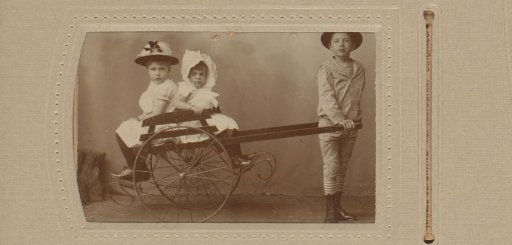 Studio portrait of two girls and a boy with a cart