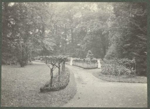 Garden path of De Paauw estate with planting on both sides in a wooded environment