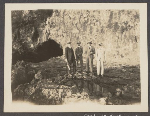 Four men at the entrance of a cave