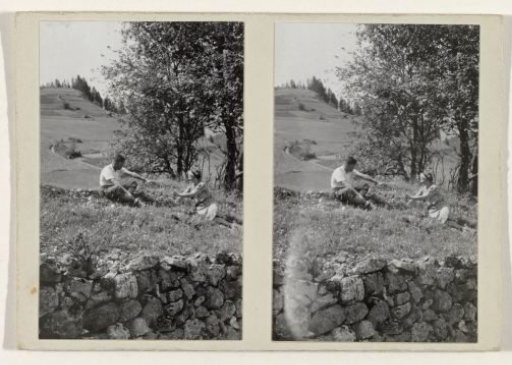 Man and woman sitting in a grassy field amidst a mountain landscape