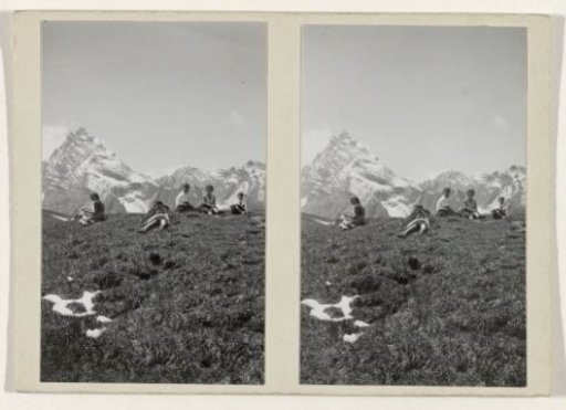 Resting people in a grassy field amidst snow-capped hills