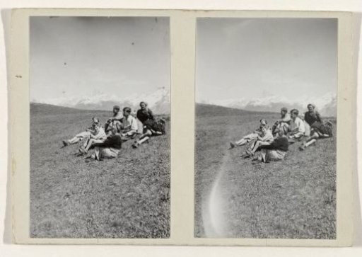 Resting people in a grassy field amidst snow-capped hills