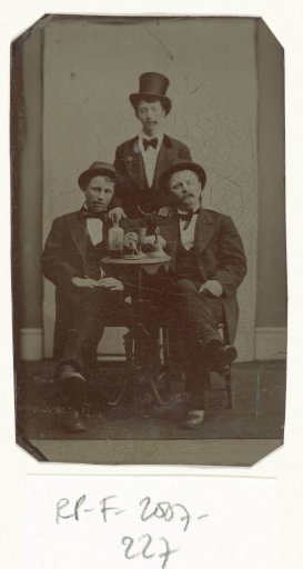 Portrait of three men at a table, drinking and smoking cigars