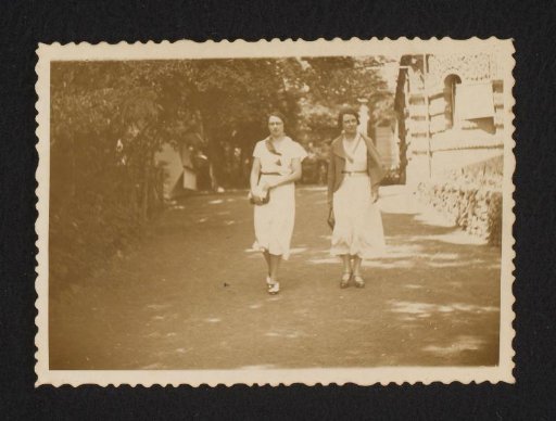 Two women walking along a shady street
