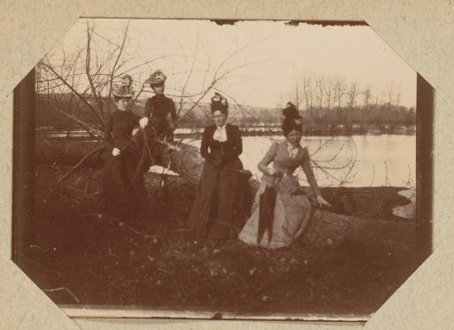 Four women by felled trees along a river