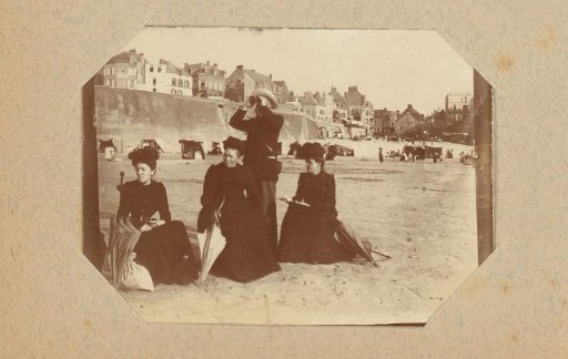 Three women and a man with a telescope on a beach