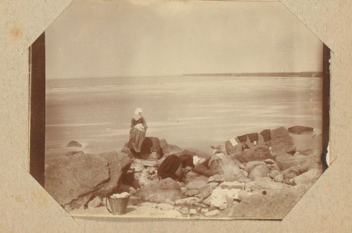 Two women with laundry among rocks on the coast