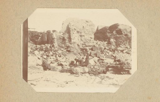 Women with laundry among rocks near a ruin