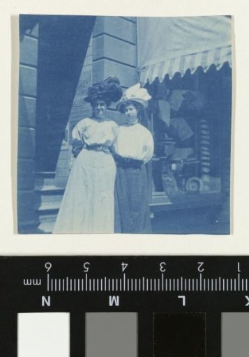 Portrait of two unknown women standing by a shop