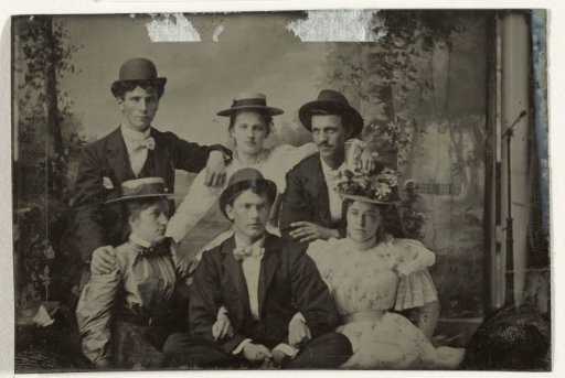 Group portrait of three men and three women, seated in an atelier with a painted backdrop (forest or park scene)